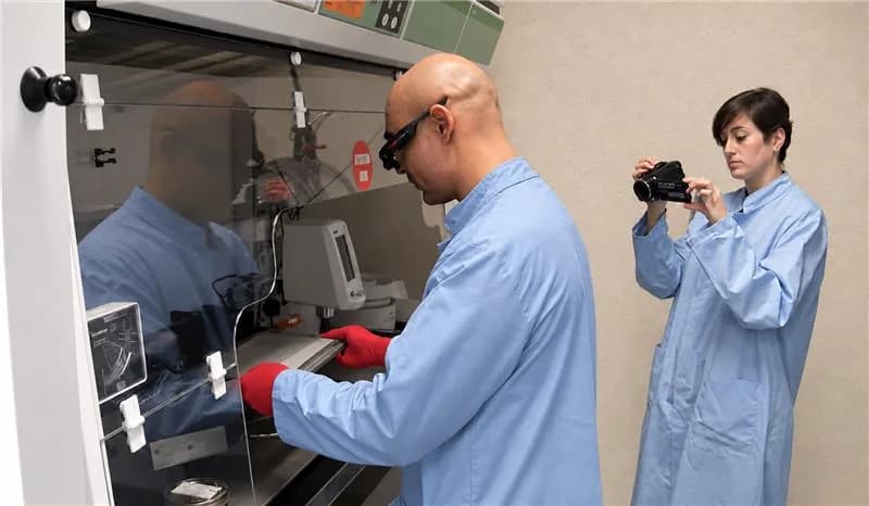A person films an operator at a workstation